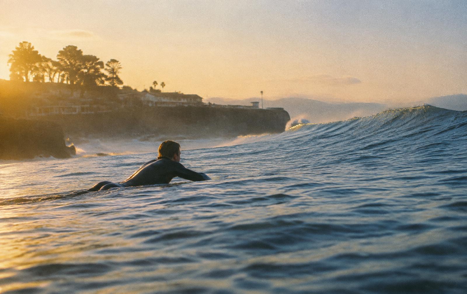 Surfer paddling out at dawn in Santa Cruz